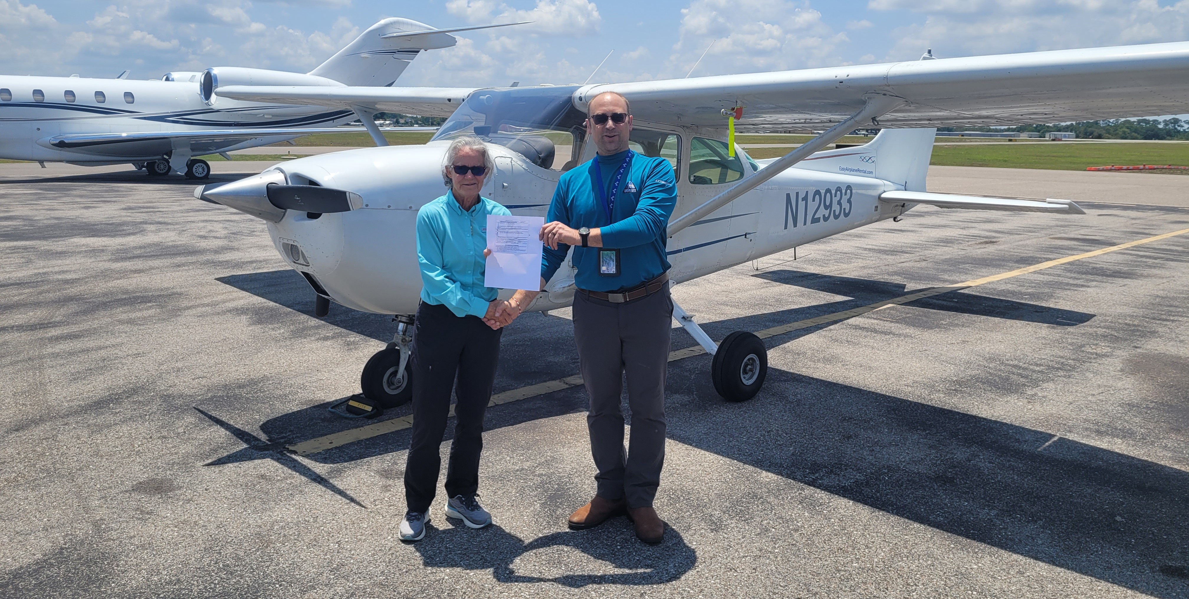 Standing at a local airport, Mark Ladwig receives his certified flight instructor license from veteran instructor 