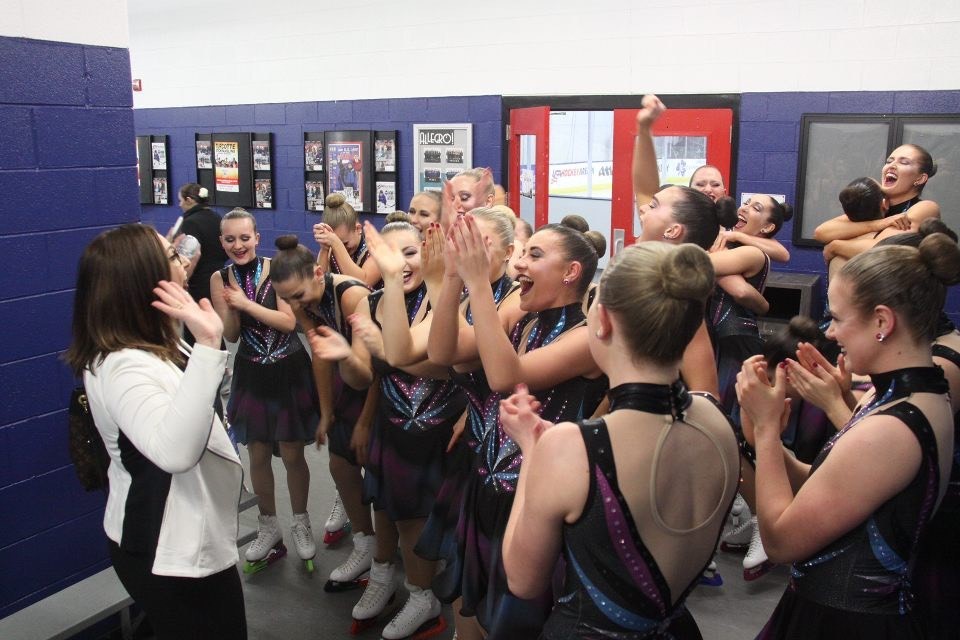 Carla DeGirolamo tells the 2019 Miami collegiate team that they won the U.S. title. They stand in a hallway outside a locker room, smiling, hugging and jumping up and down.