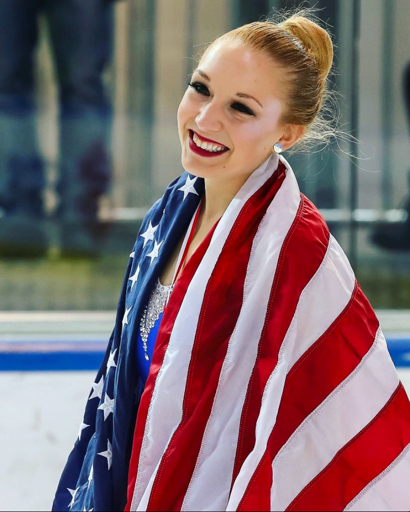 Casey Ouellette smiles in a portrait with the American flag draped around her.