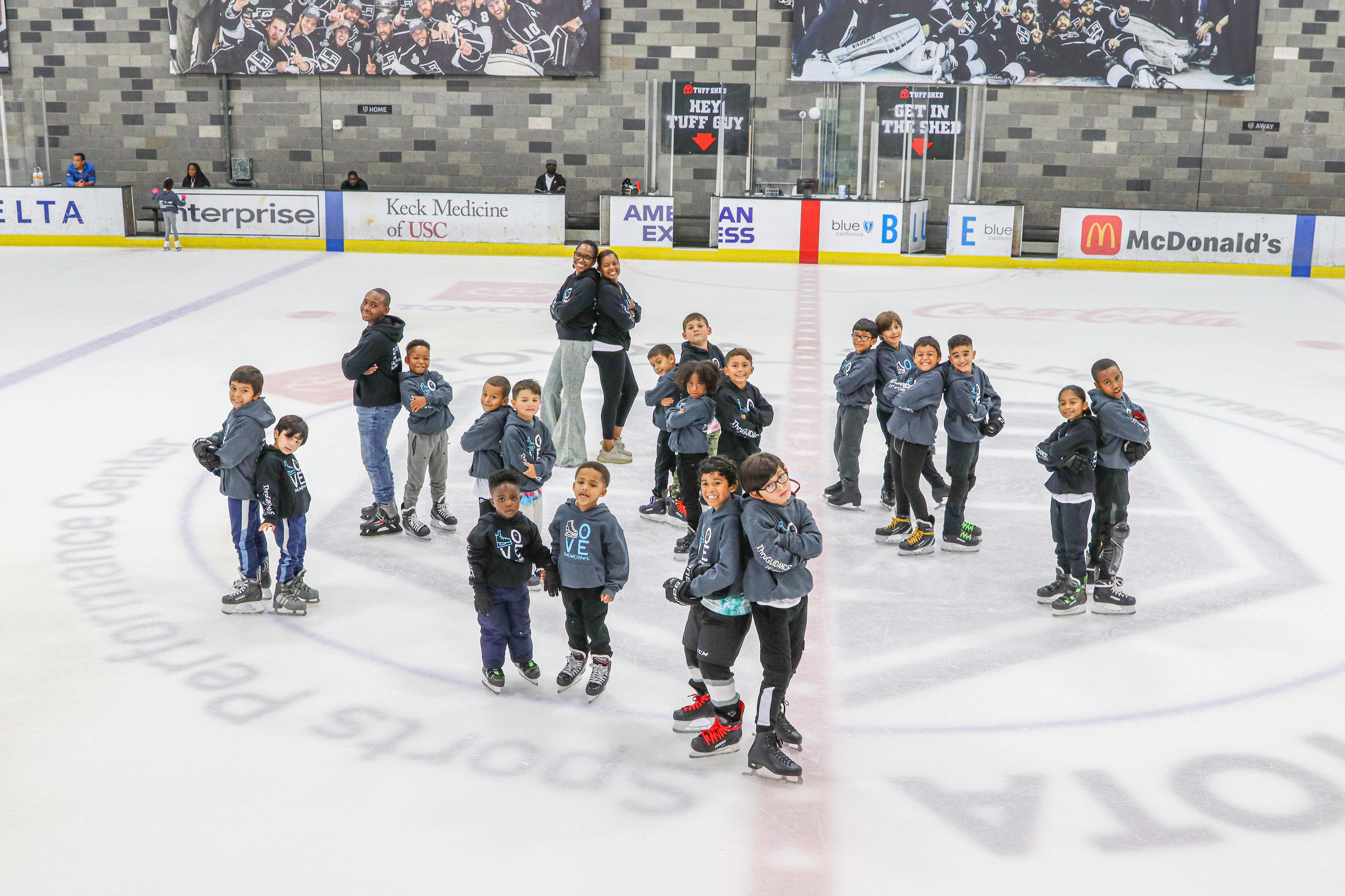 Young boys in gray shirts skating on the ice.