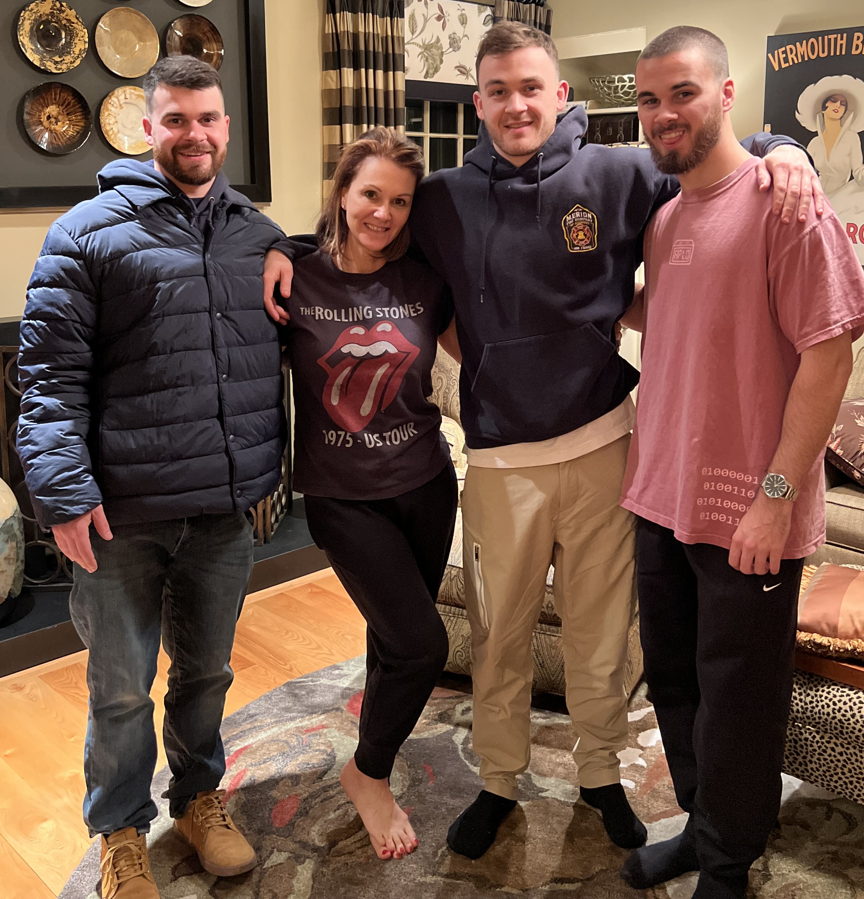 April poses with her three sons. They all have their arms around each other. April is wearing a Rolling Stones tshirt. One son is wearing a blue puffy winter coat, one is wearing a blue hoodie and the other is wearing a pink tshirt. 