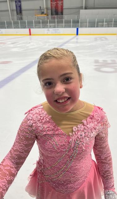 Blakely Schroeder, dressed in pink, stands proudly on the ice.