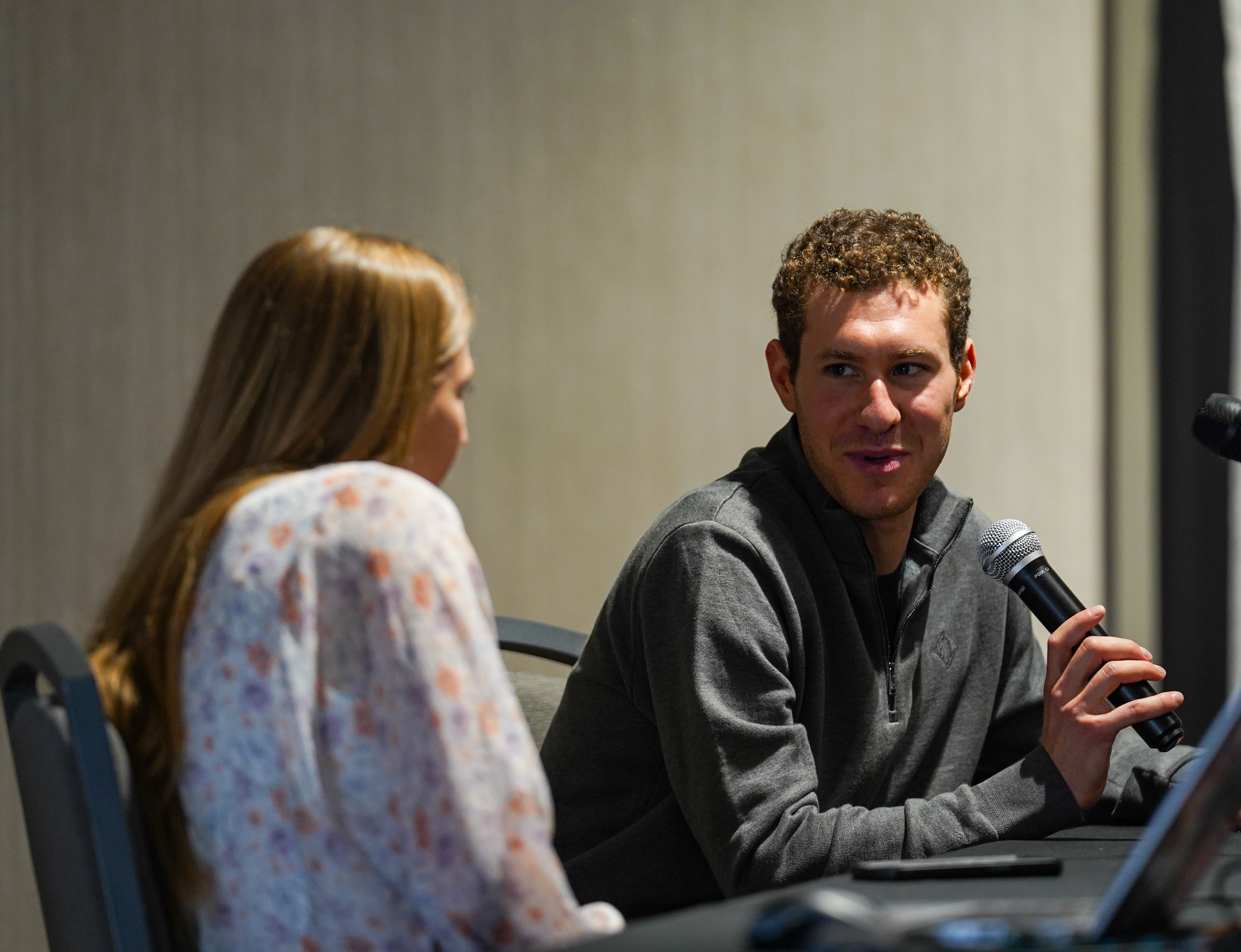 Jason Brown answers questions holding a mic posed by fellow Olympian Polina Edmunds.