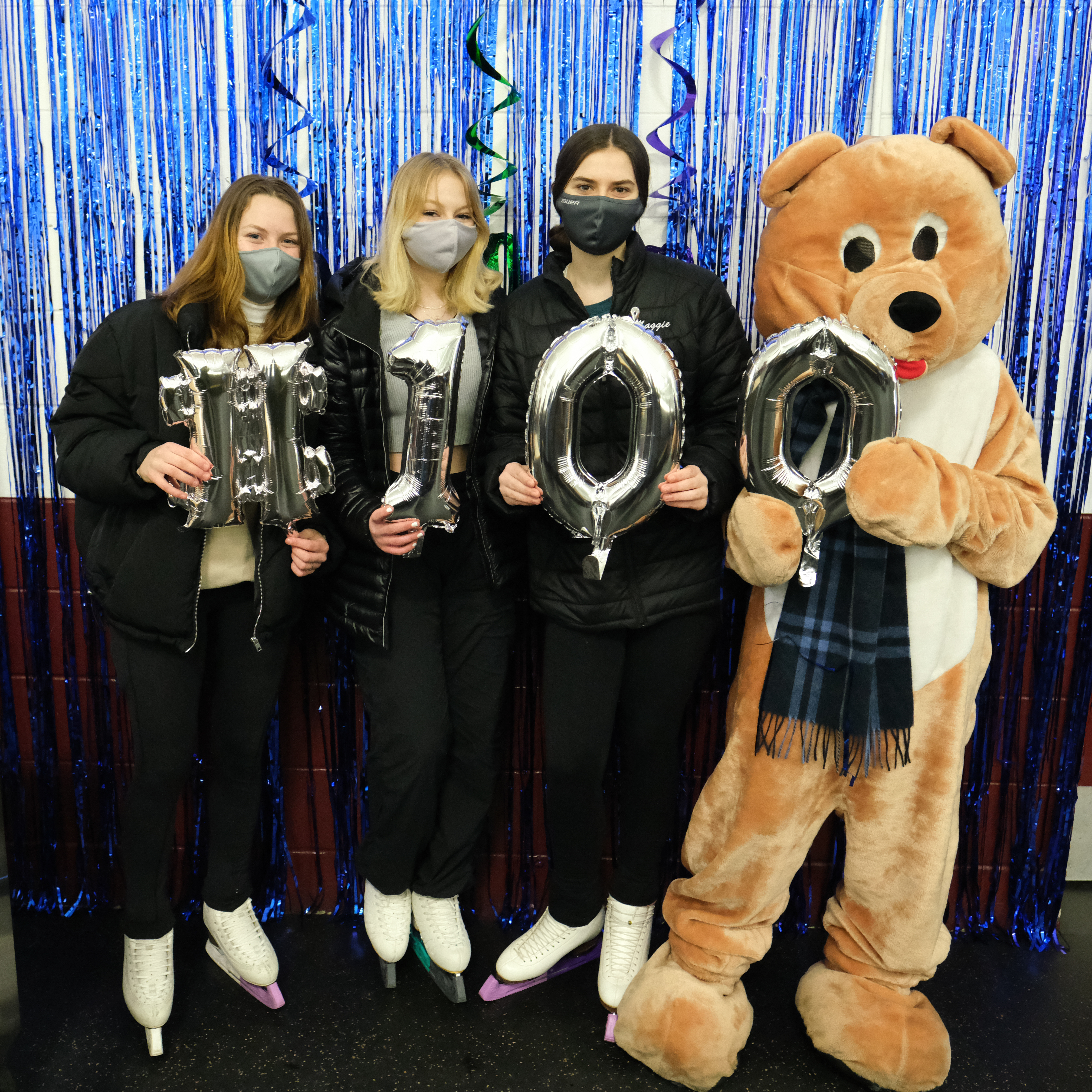 FSC of Minneapolis skaters hold up balloons spelling out 100 with a bear mascot.