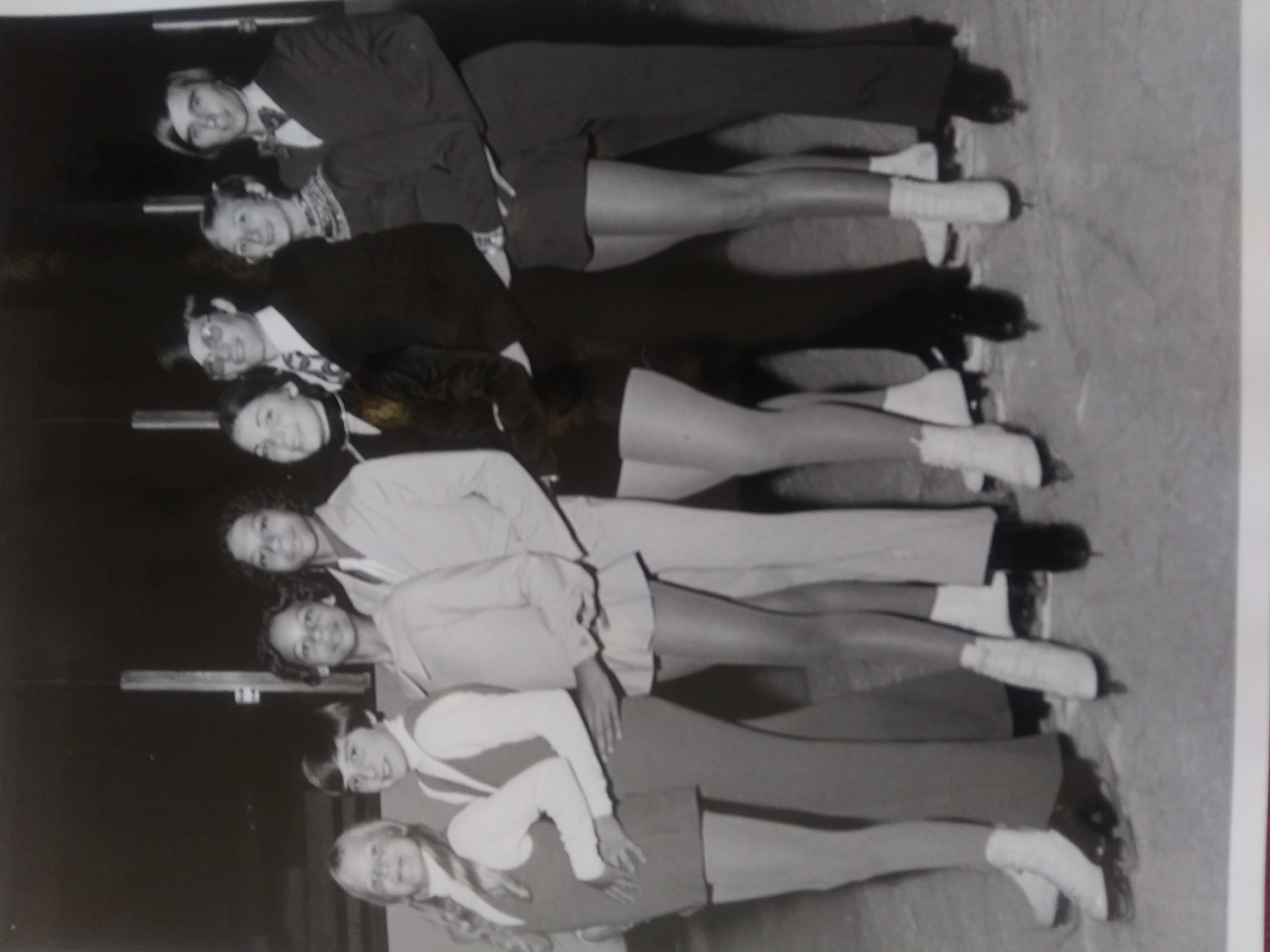 Black and white photo of Alan and Ellen as kids. Alan and Ellen stand in the middle of the group. They are young African American skters wearing light colored skating costumes