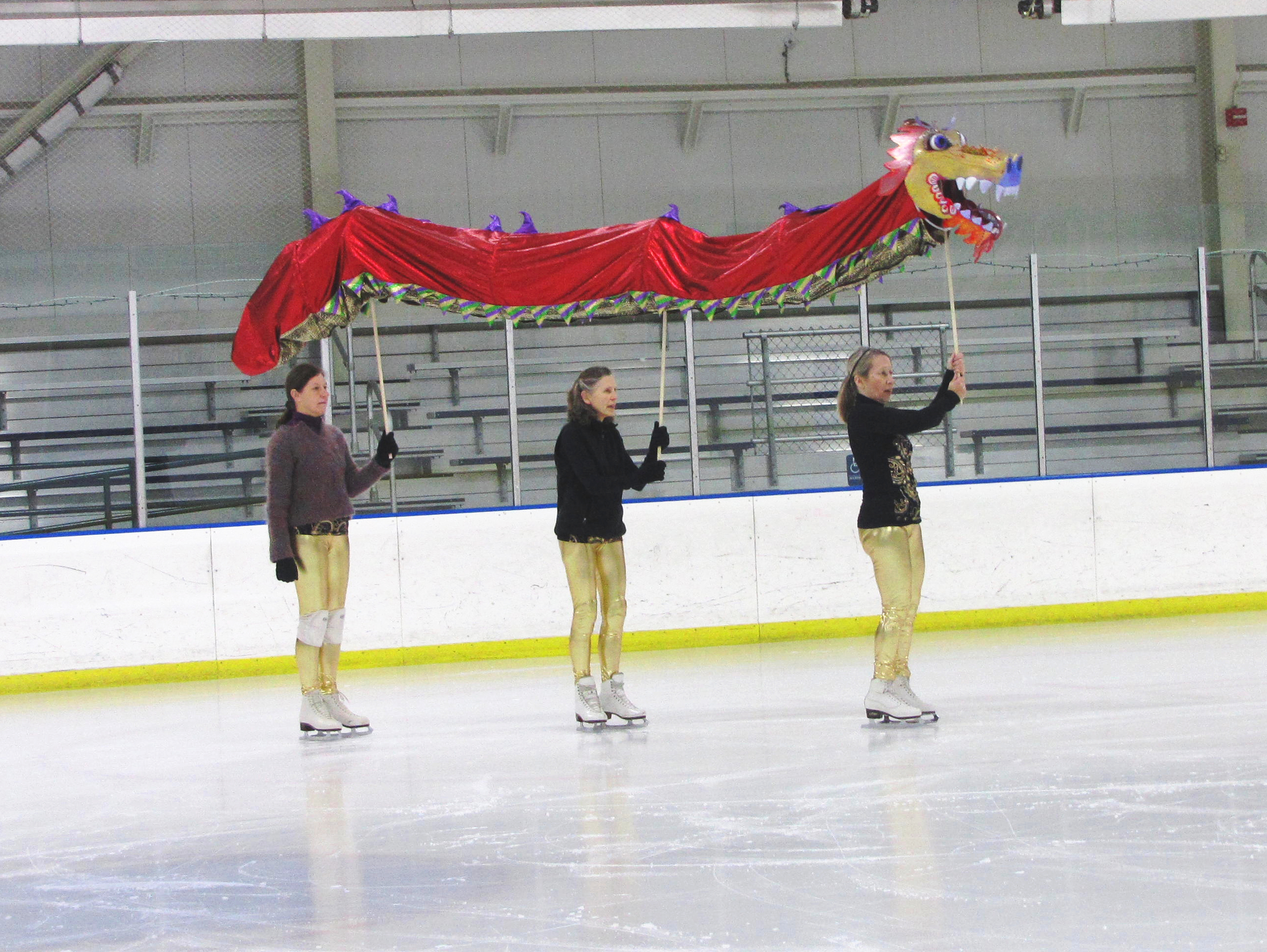 Janet Long, Caroline Thorington and Carol Dors carry a big Chinese New Year dragon across the ice.