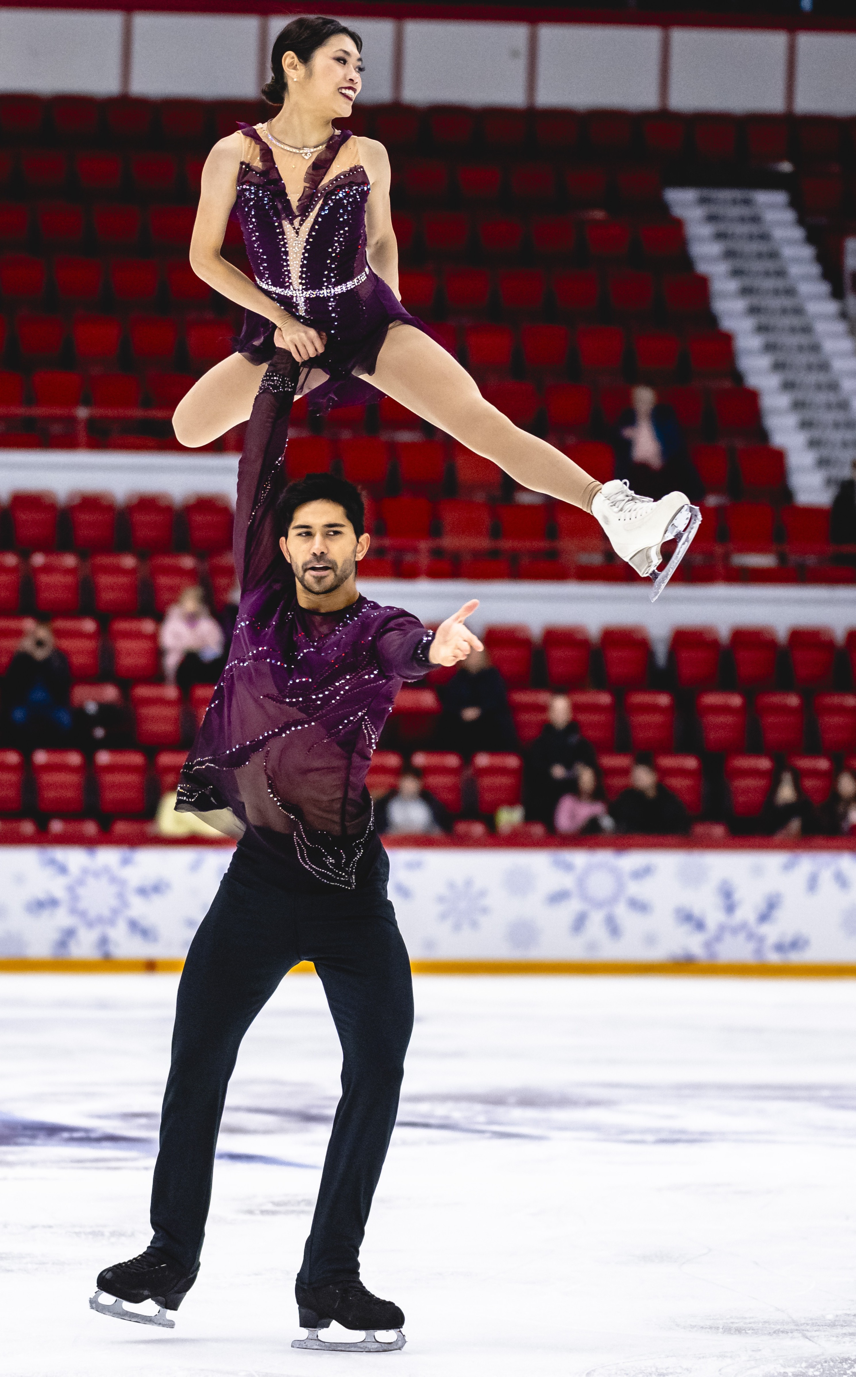 Dressed in purple and black, Spencer Howe lifts Emily Chan high into the air.