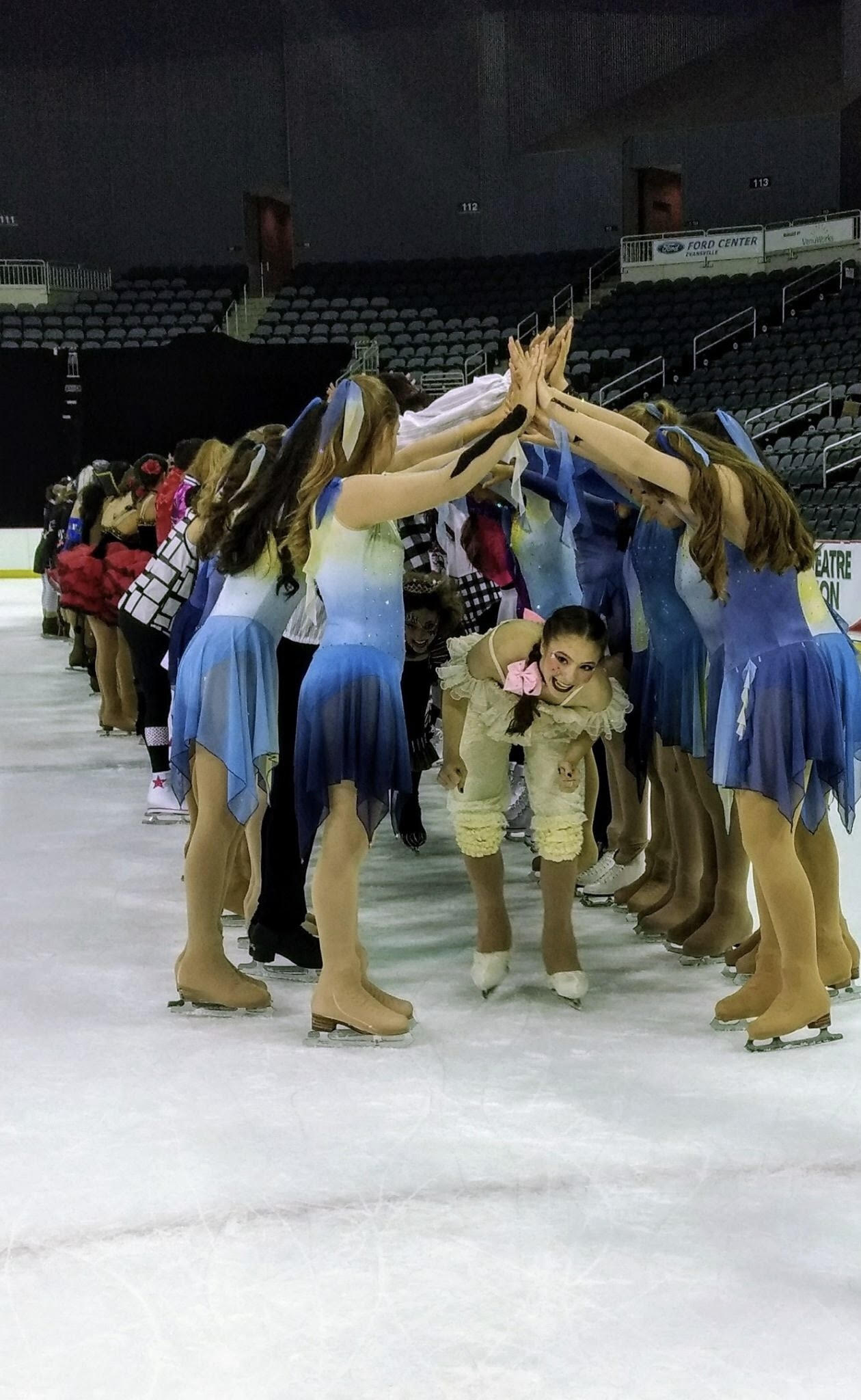 Harmony Ice Theatre forms a human tunnel and one skater skates through.
