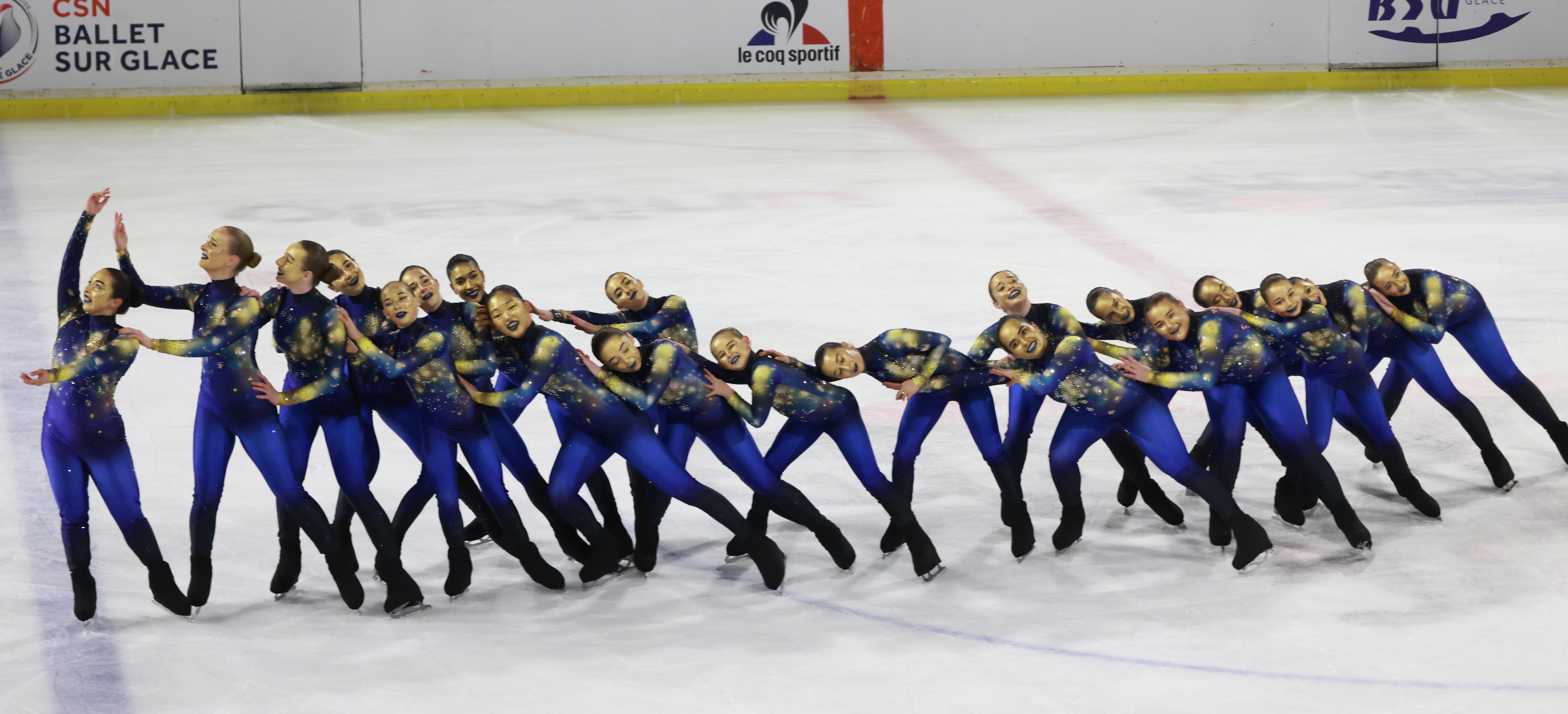 Houston Ice Theatre all stand in a line leaning on each other wearing matching blue costumes that look like a galaxy