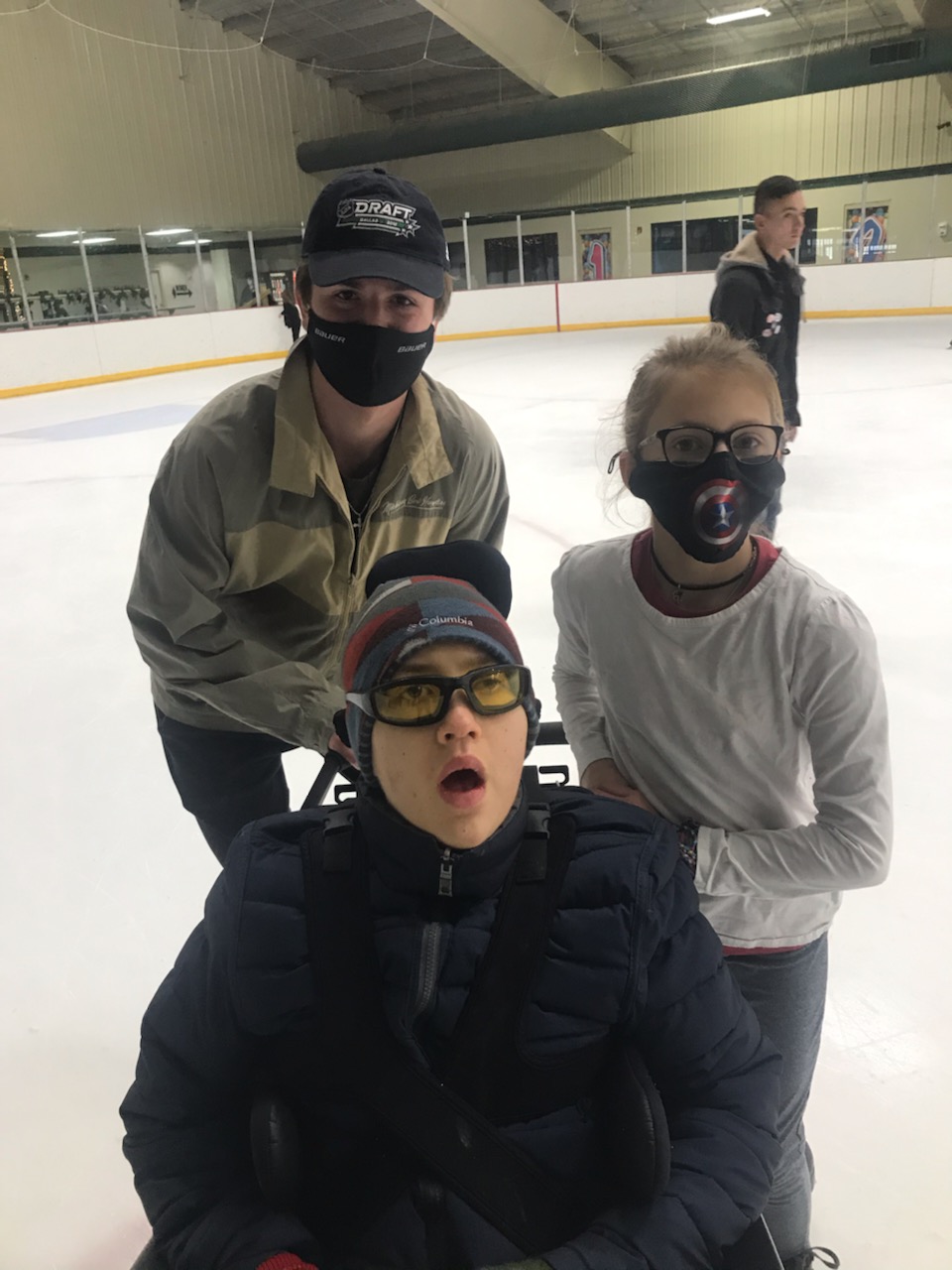 Rye poses for a photo on the ice with his friend and sister.