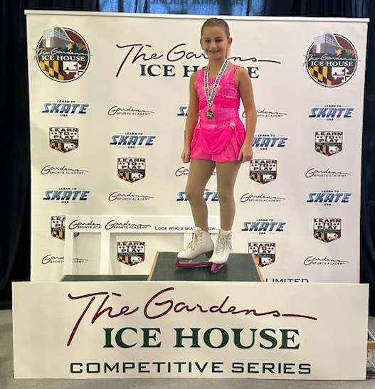 A skater in one of the rental costumes stands on the podium 