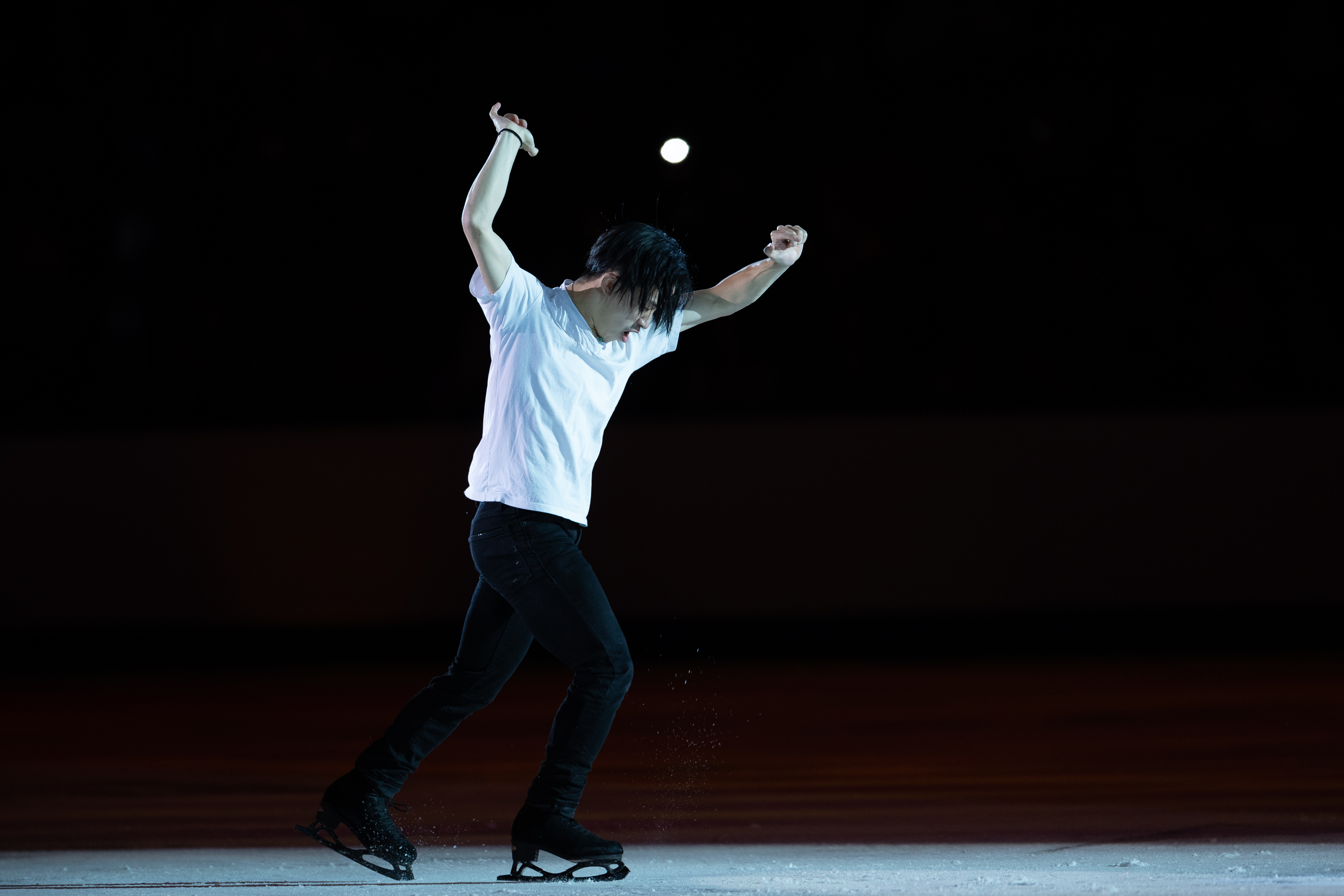 Jimmy Ma skating in a white t-shirt under a spotlight.