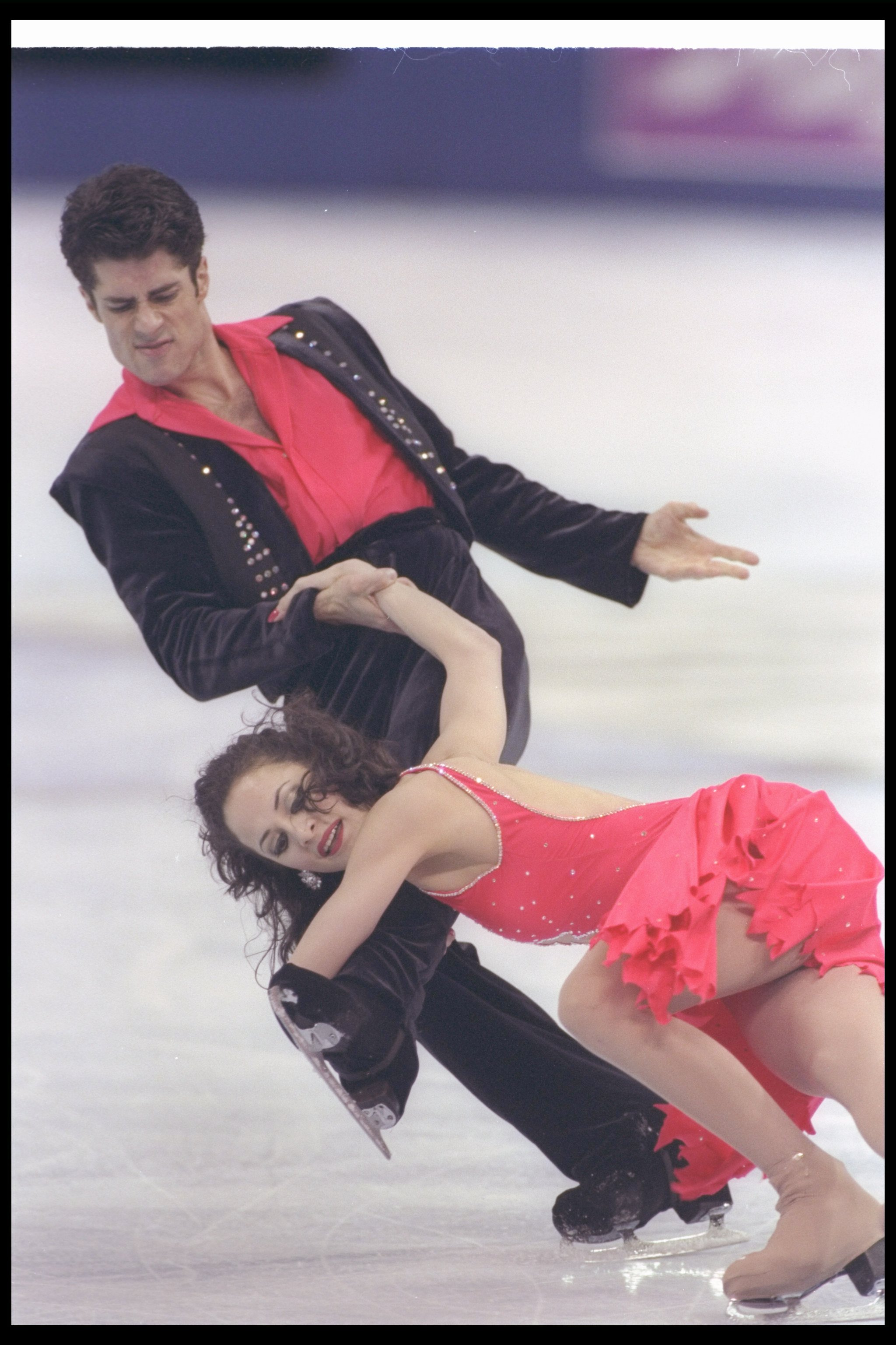 Jerrod and Elizabeth in red and black leaning to the side on the ice