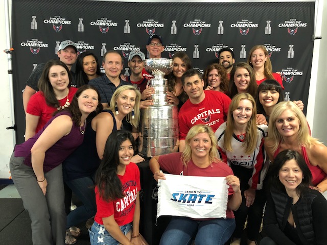 A group of people in red pose with the Stanley Cup.