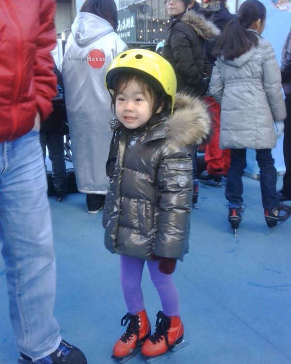 Three-year-old Logan Higase-Chen, dressed in yellow helmet, gray coat, purple pants and red skates, takes to the ice.