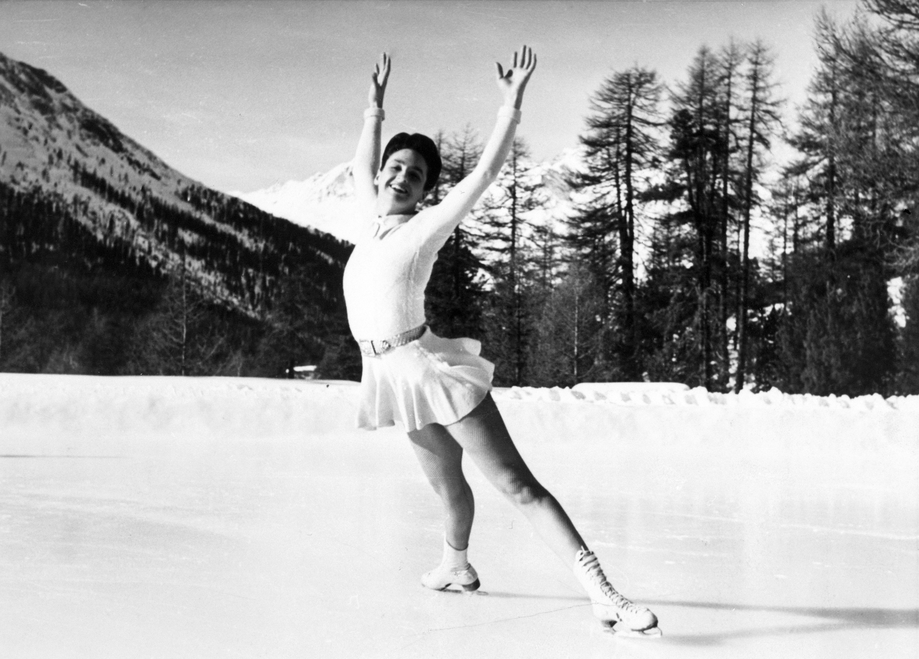In a black and white photo, Maribel Vinson outstretches her arms while skating on an outdoor ice rink.
