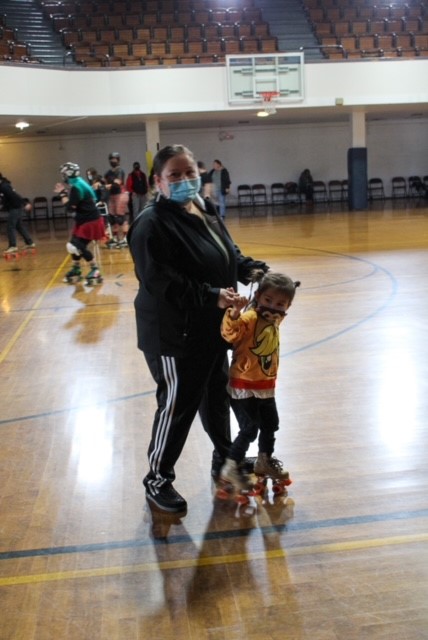 A mom holds up a young boy wearing roller skates.