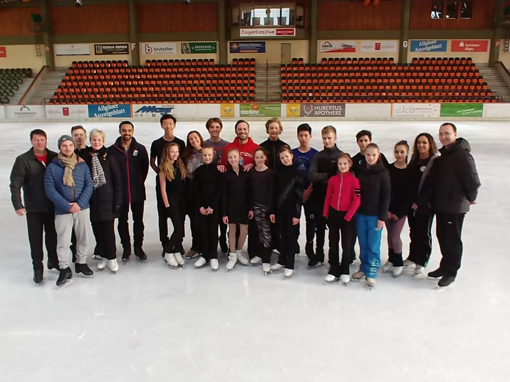 A big skating group poses on the ice.