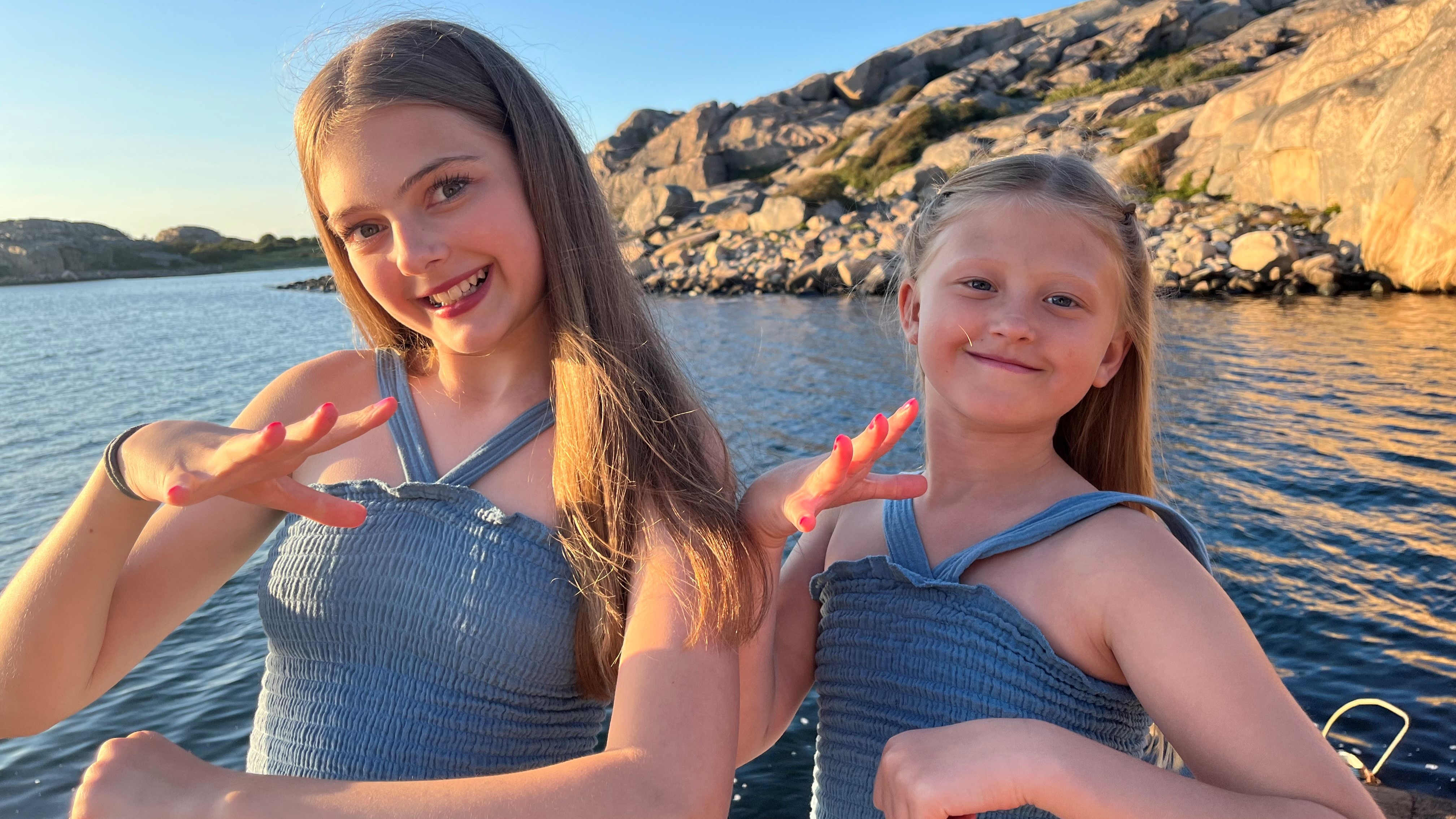 Out on a boat in the water, Odessa Akervall and her cousin Ofelia, dressed in green dresses, sign xxx.