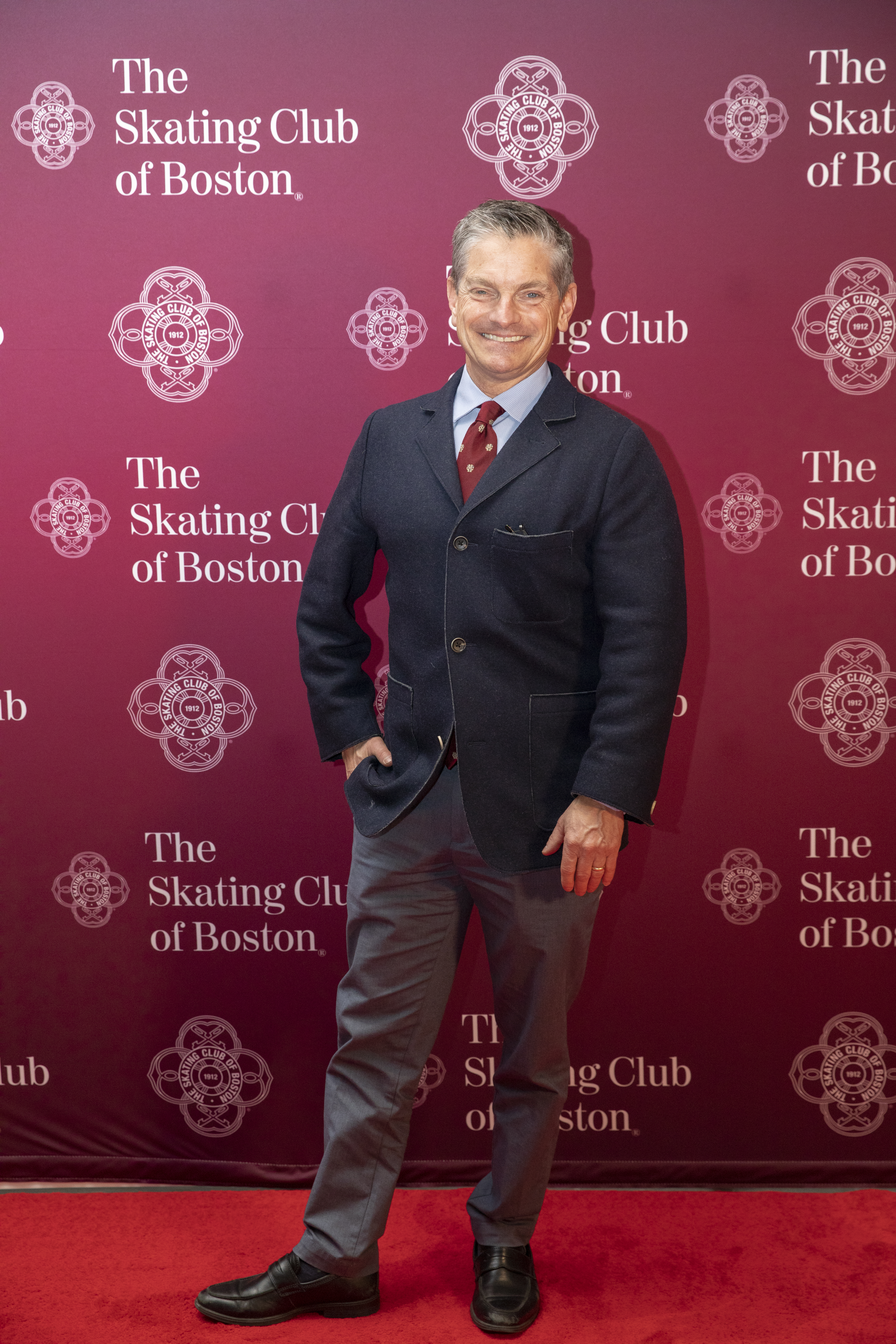 A full body shot of Paul Wylie on a red carpet in business casual clothing.