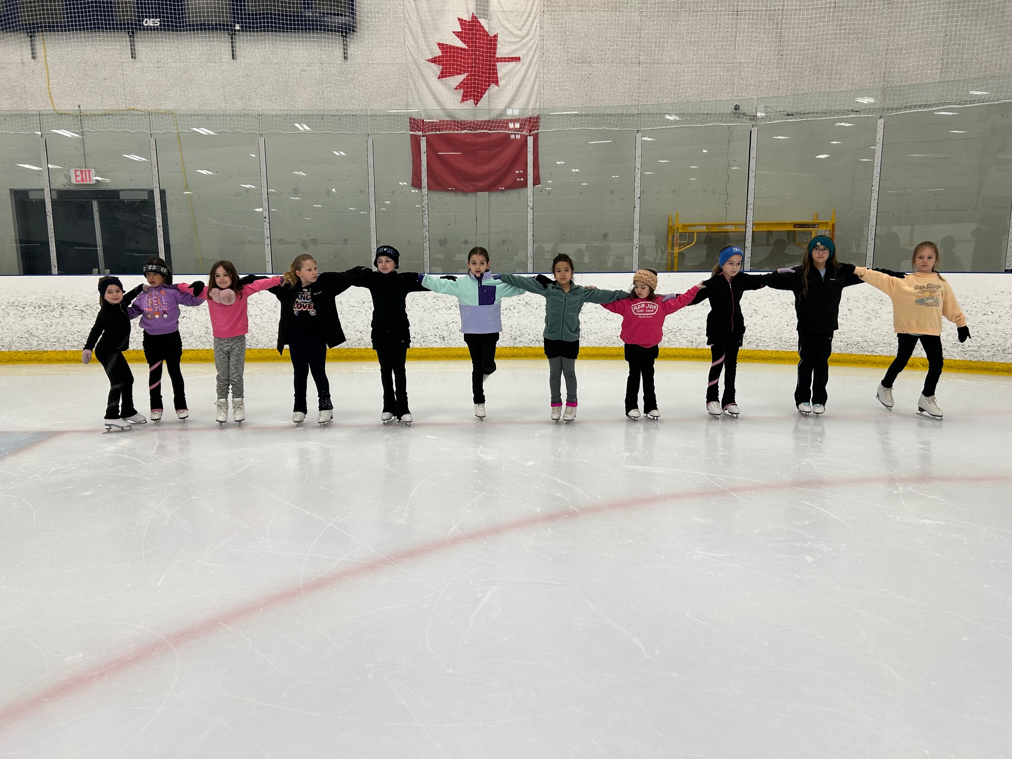 Members of the Tuesday with Amy skate club prepare for practice (standing with arms locking).