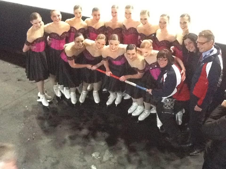 An above shot of a synchro team off the ice holding a spirit stick.