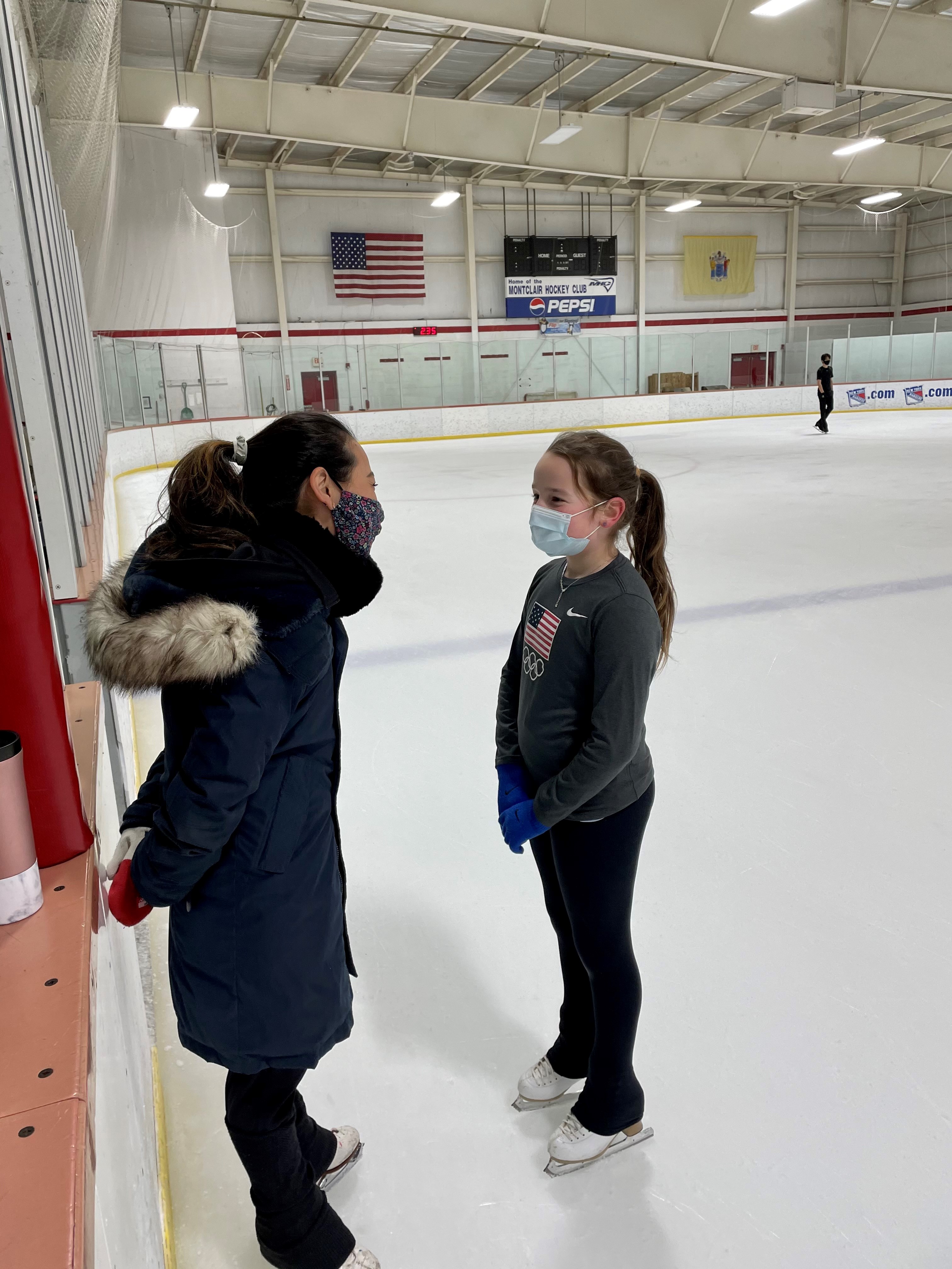 Felicia Zhang talks to a young student on the ice.