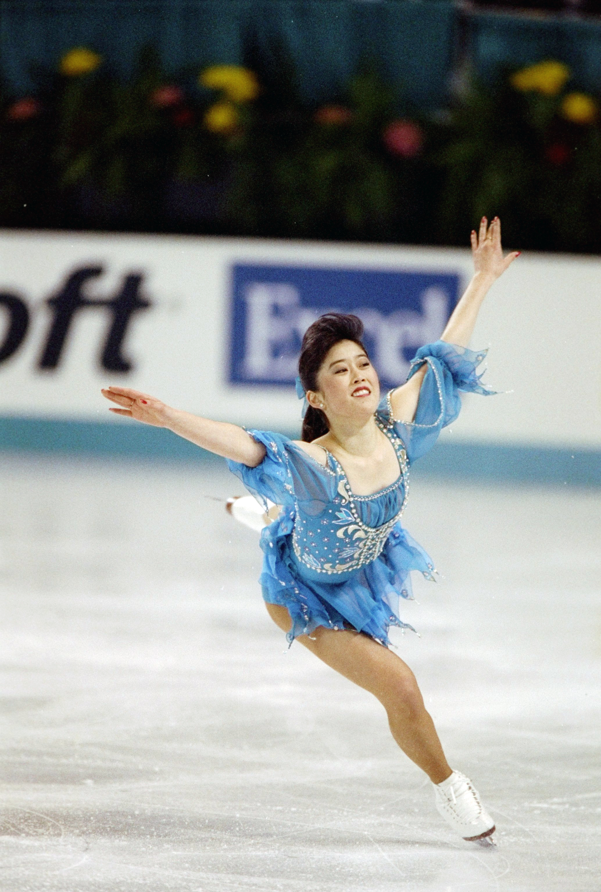 Wearing a blue dress, Kristi Yamaguchi lands a jump at the 1992 World Championships.