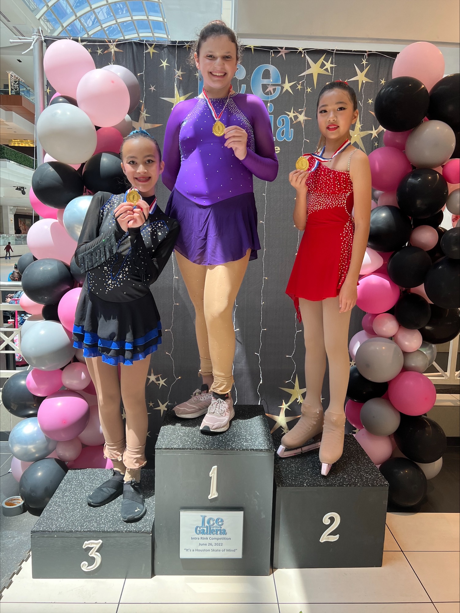 Three young female skaters stand on a podium