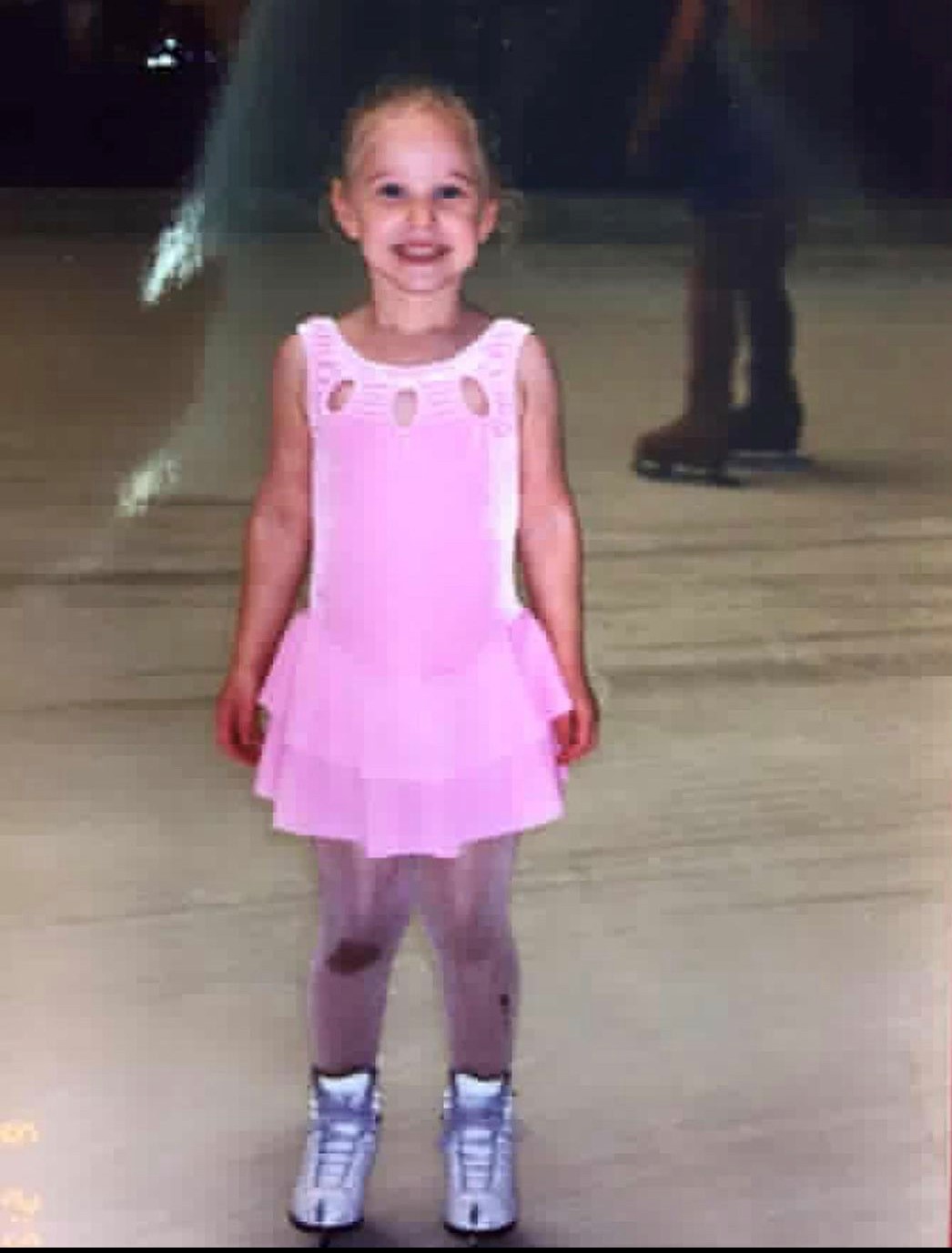 Sarah Fuller on the ice as a young child, wearing a pink dress.