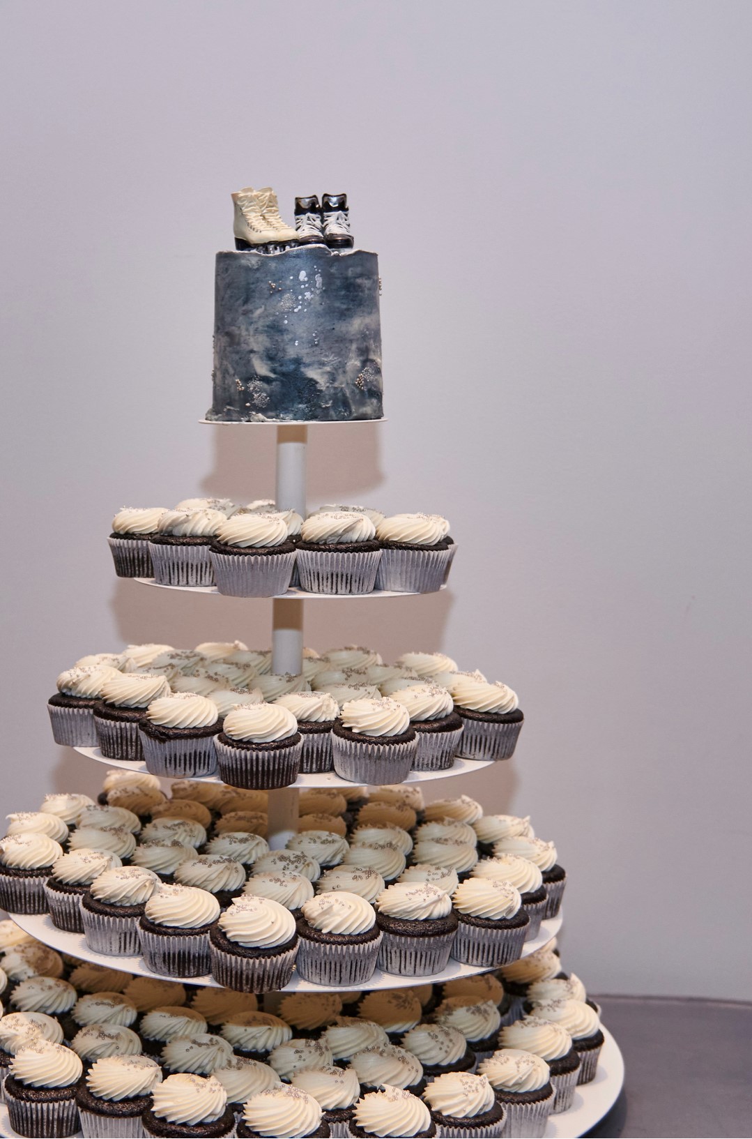 Cupcakes with white frosting arranged to look like a wedding cake with a small pair of skates on top