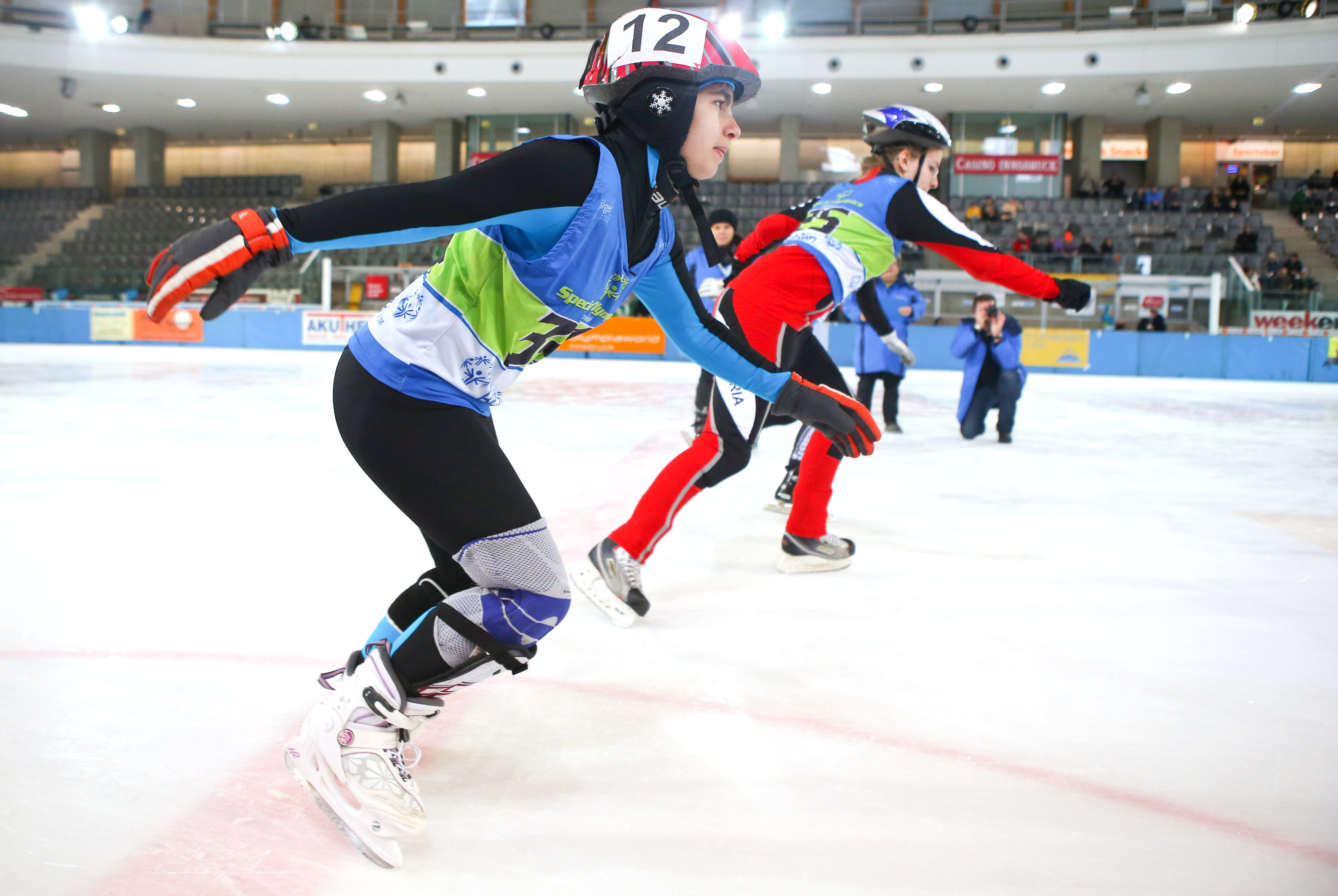 A group of Special Olympics speed skaters race to the finish line wearing hockey skates.