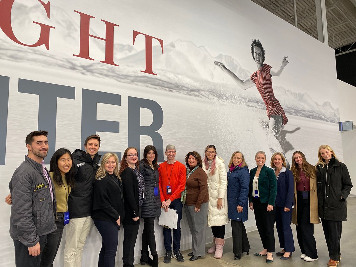A group of former Team USA athletes stand in front of the Tenley Albright Performance Center banner in Boston following their trial judge assignment at Eastern Sectionals.