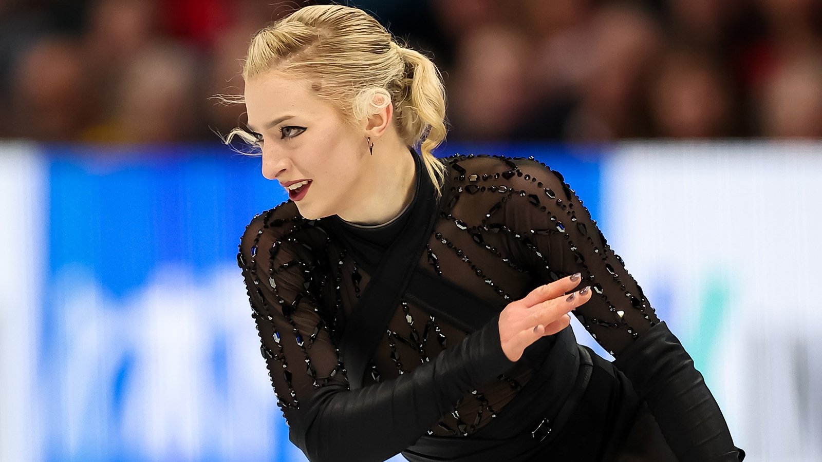 Amber Glenn, wearing a beeded black costume, looks to the side, with one arm lifted and one hanging down.