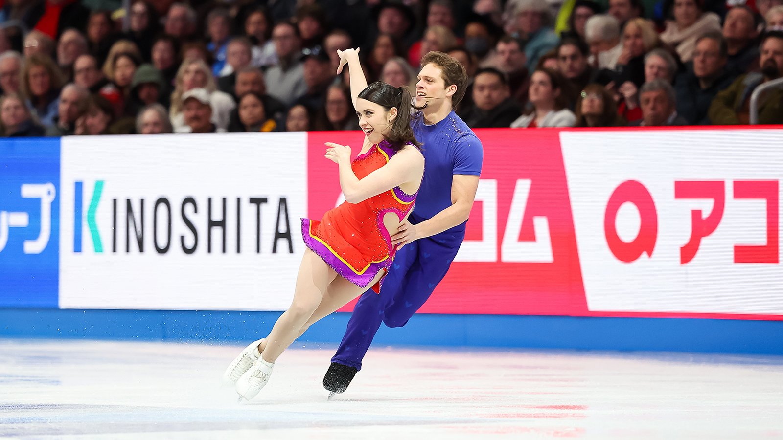 Caroline Green, dressed in red, and Michael Parsons, dressed in blue, skate side by side at the 2025 World Championsships.