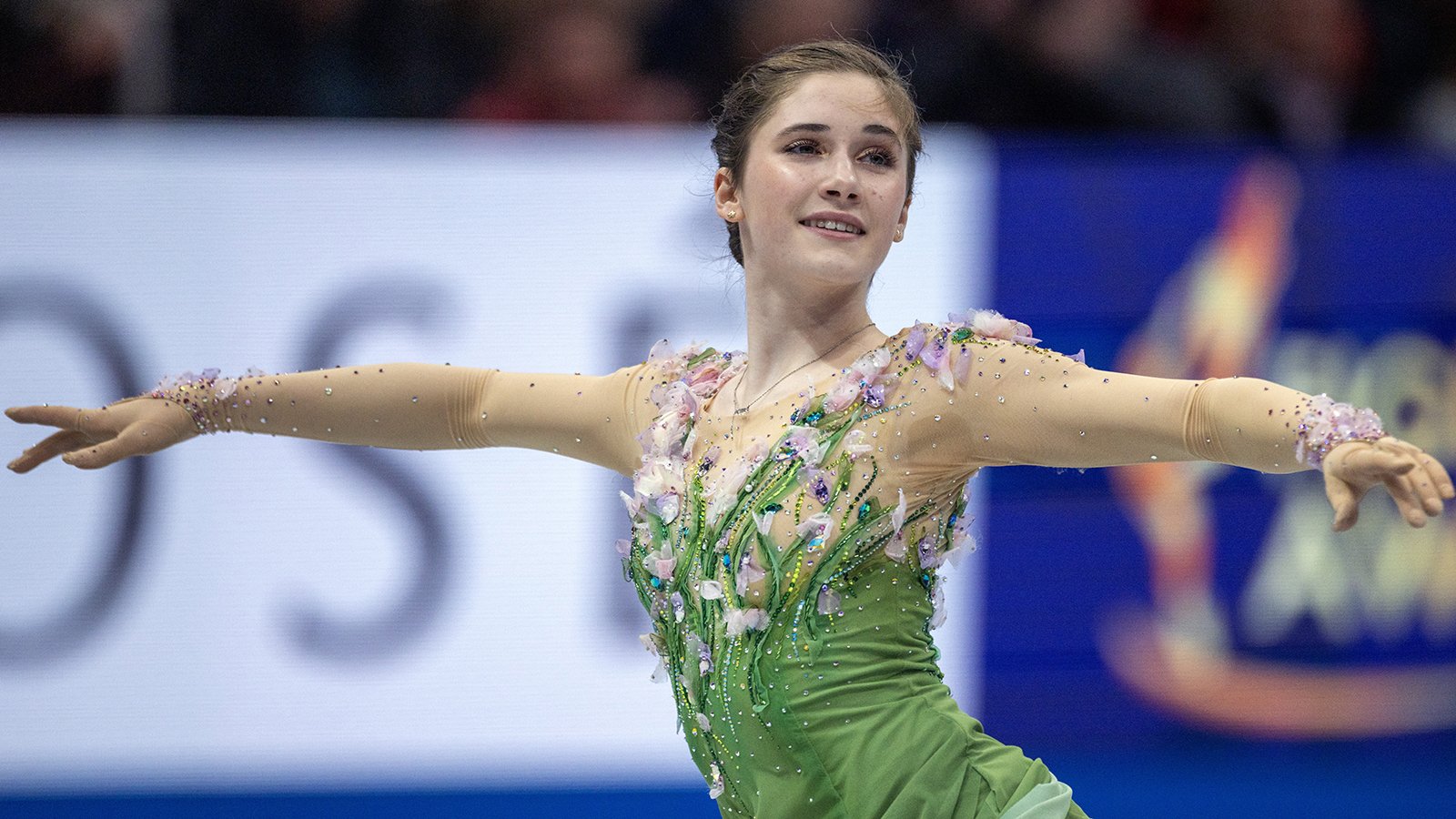 Dressed in green, arms extended, Isabeau Levito competes at the World Championshps