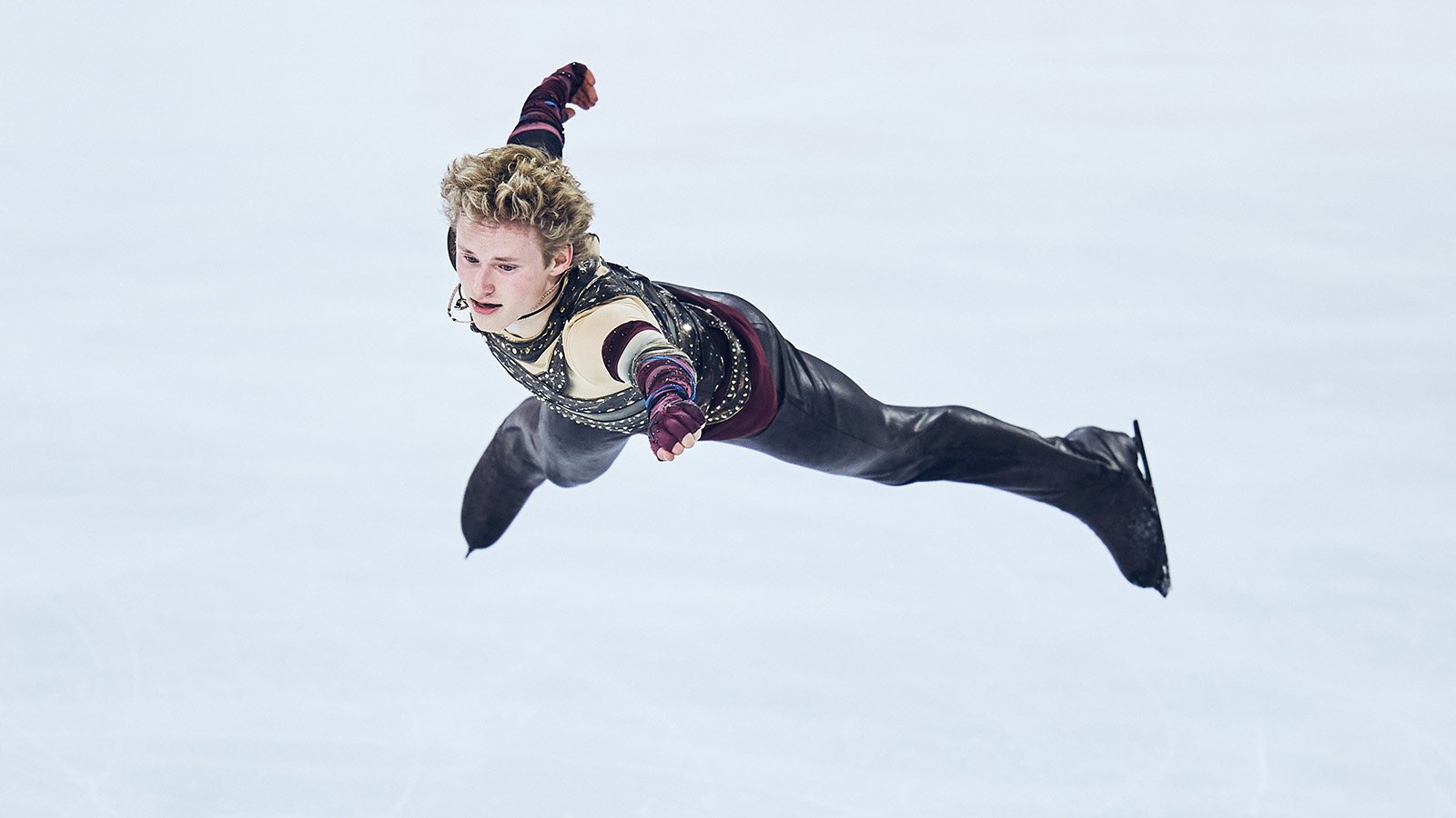 Ilia Malinin soars in the air, legs and arms spread