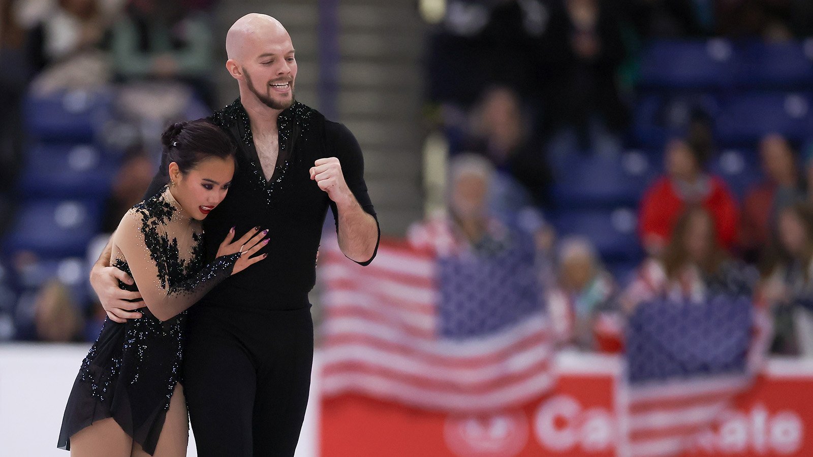 Danny O'Shea pumps his fist as he puts his other arm around partner Ellie Kam as they skate off the ice at Skate Canada International