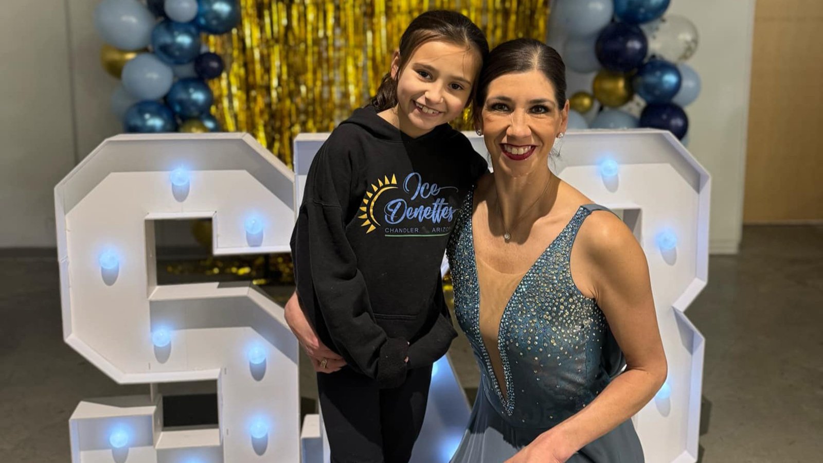 Dressed in black, Elora stands next to her mother, Naomi Lang, who just competed as member of the IceDenettes. 