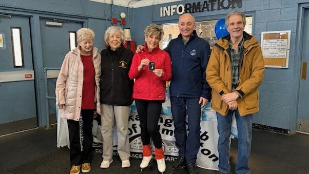 Sharon Rzaza, red coat, receives her ice dance gold medal, surrounded by friends and her coach.