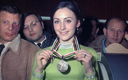 Peggy Fleming shows off her gold medal, surrounding by reporters, at the 1968 Olympic Games.
