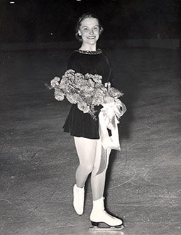 Carol Heiss poses with flowers while looking at the camera