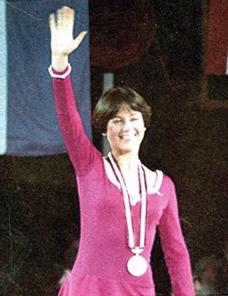Dorothy Hammill waves to the crowd atop the podium at the 1976 Olympic Winter Games