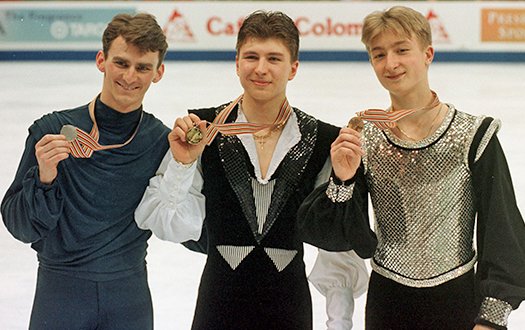 Tood Eldredge is joined by Alexei Yagudin (center) and Evgeni Plushenko (right), who are all showing their medals to the camera.