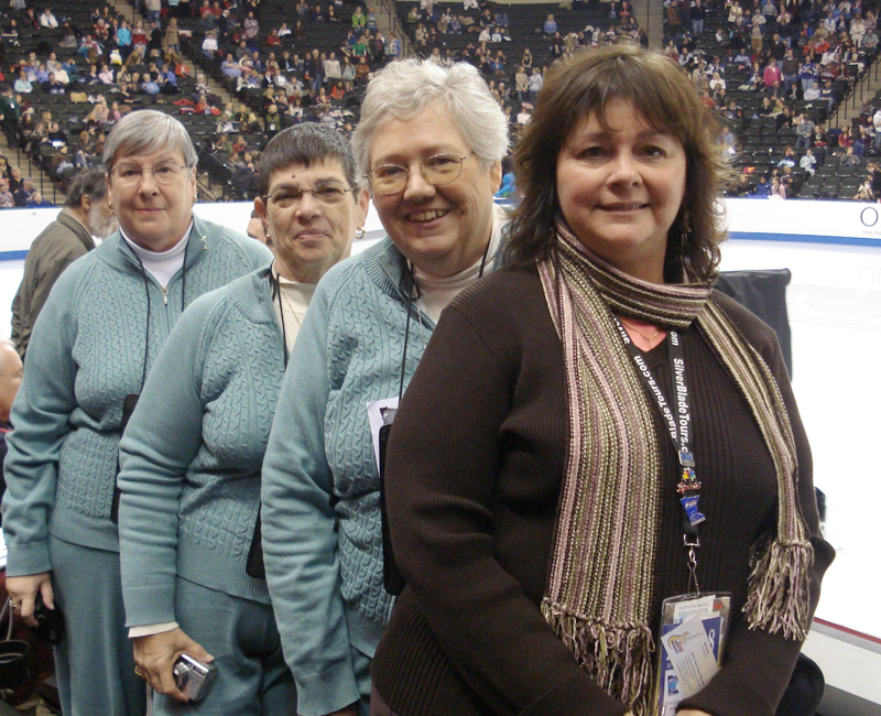 Group of women standing next to ice skating rink
