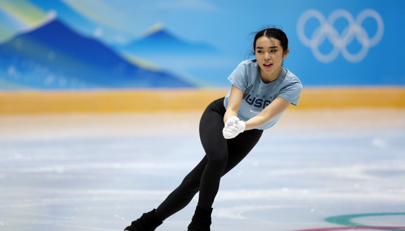 Karen Chen on practice ice at the 2022 Olympics, with the rings on the boards behind her.