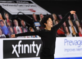 Donning a flowing black long sleeve shirt, Nathan Chen skates with his arms outstretched at the 2021 Toyota U.S. Figure Skating Championships.