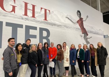 A group of former Team USA athletes stand in front of the Tenley Albright Performance Center banner in Boston following their trial judge assignment at Eastern Sectionals.