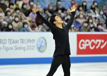 Nathan Chen, wearing all black, ends his program with his arms outstretched towards the air.