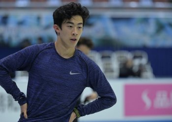 Nathan Chen, wearing a navy blue short, rests his hands on his hips during practice.